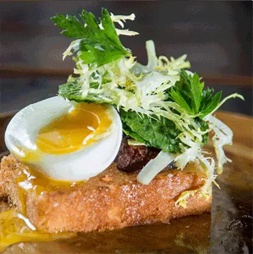 Toast topped with a soft-boiled egg and fresh greens