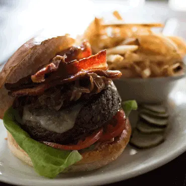 Burger with lettuce and tomato served beside fries