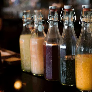 Glass bottles filled with colorful mixers lined up at the bar