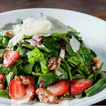 Strawberry and spinach salad with shaved cheese and nuts