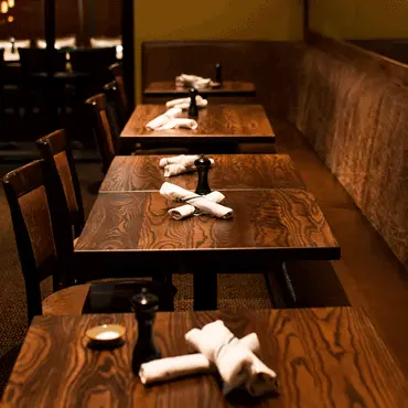Wooden dining tables set with folded napkins