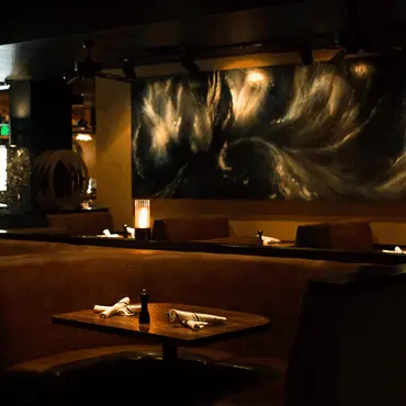 Dimly lit dining area with wall art and table settings