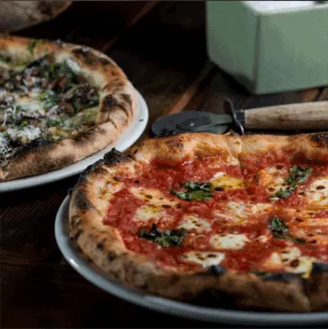 Two pizzas with tomato, cheese, and herbs